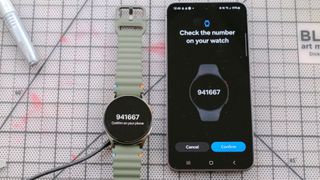 Samsung Galaxy Watch 7 next to a Samsung Galaxy S24 smartphone with each showing a matching pin for pairing purposes