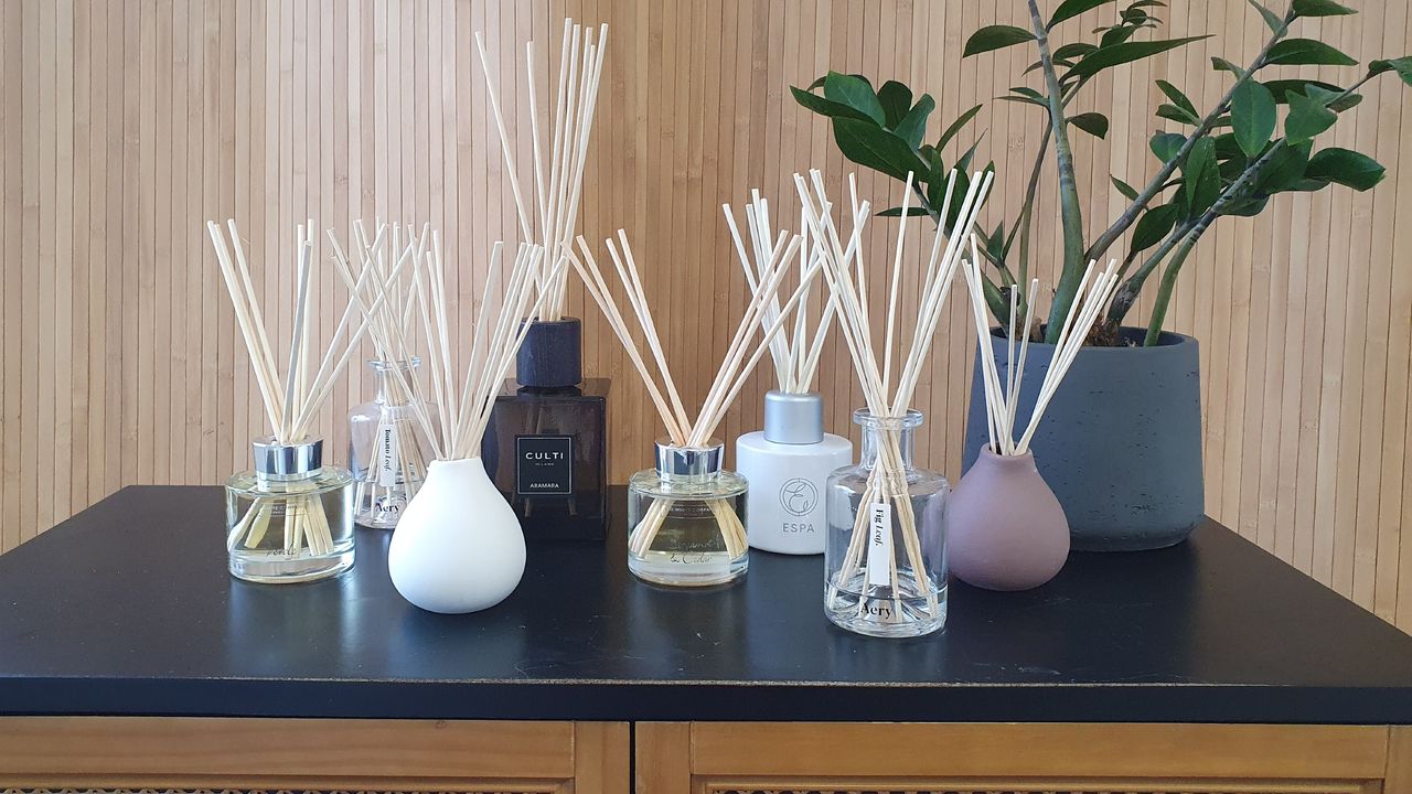 A group of reed diffusers on a cabinet next to a plant