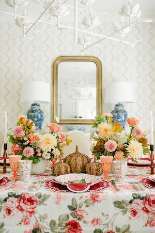 fall table ideas with layered materials including woven rattan pumpkins, linen tablecloth and napkins, fresh flowers, and ceramic tableware