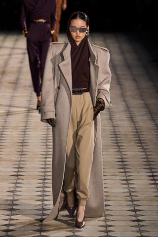 Saint Laurent models walk the spring/summer 2023 runway in a trench coat