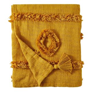 A gold, boho textured throw blanket with small fringes