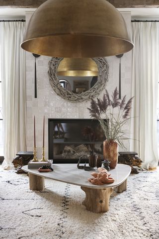A living room with an oversized lighting piece, a bespoke coffee table and a fireplace