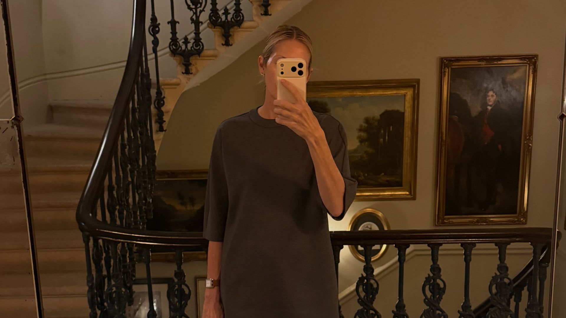 Kelly Rutherford takes a mirror selfie wearing a short-sleeve knit with dark wash jeans and a black suede bag.