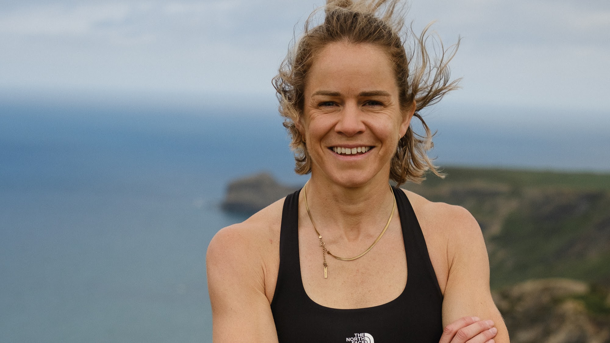 Ultra runner Elsey Davis smiles at the camera with the South West Coast Path in the background