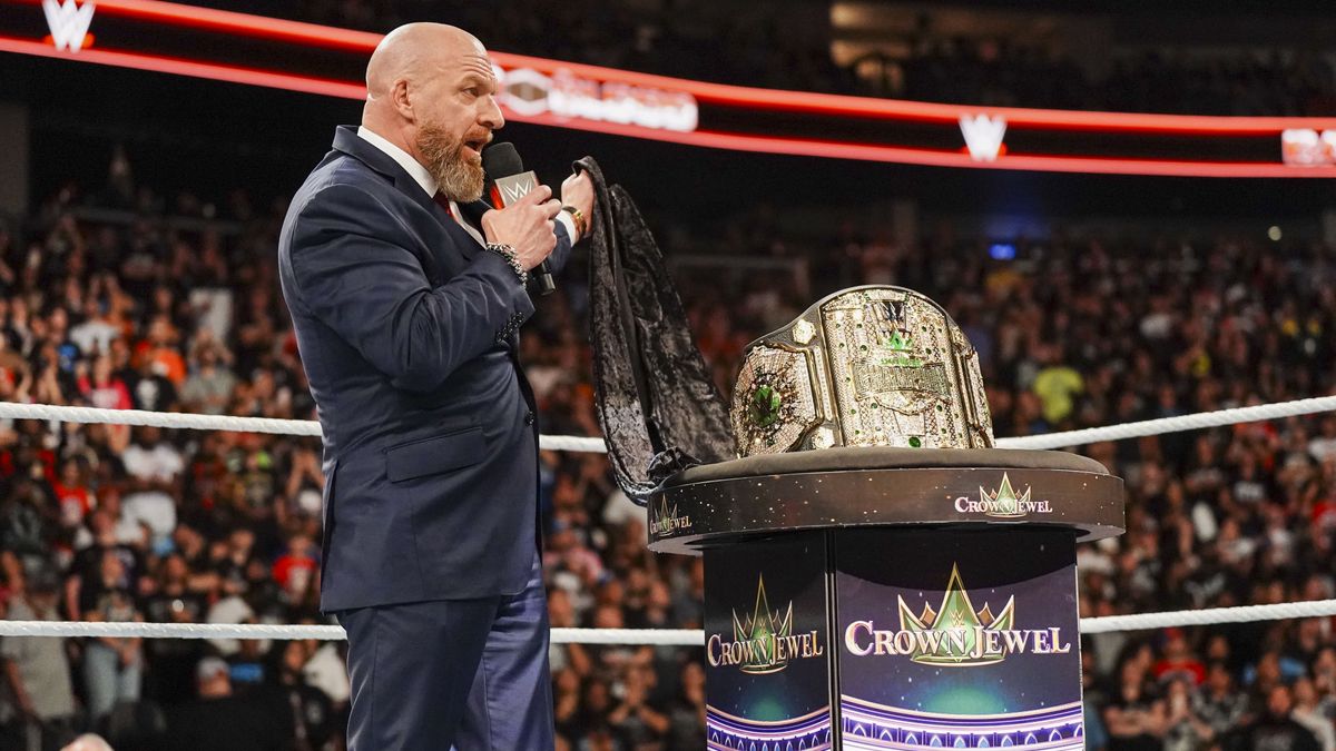 WWE Chief Content Officer Triple H in a dark blue suit presents the Crown Jewel title belt ahead of WWE Crown Jewel 2024