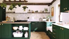 A tidy kitchen with dark green cabinets, dark wooden beams around the ceiling, white walls and cream tiles, and plants decorated around it