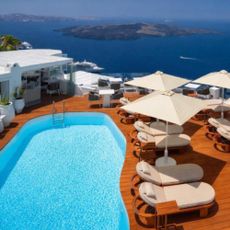 Image of a swimming pool in Greece with sun loungers and ocean