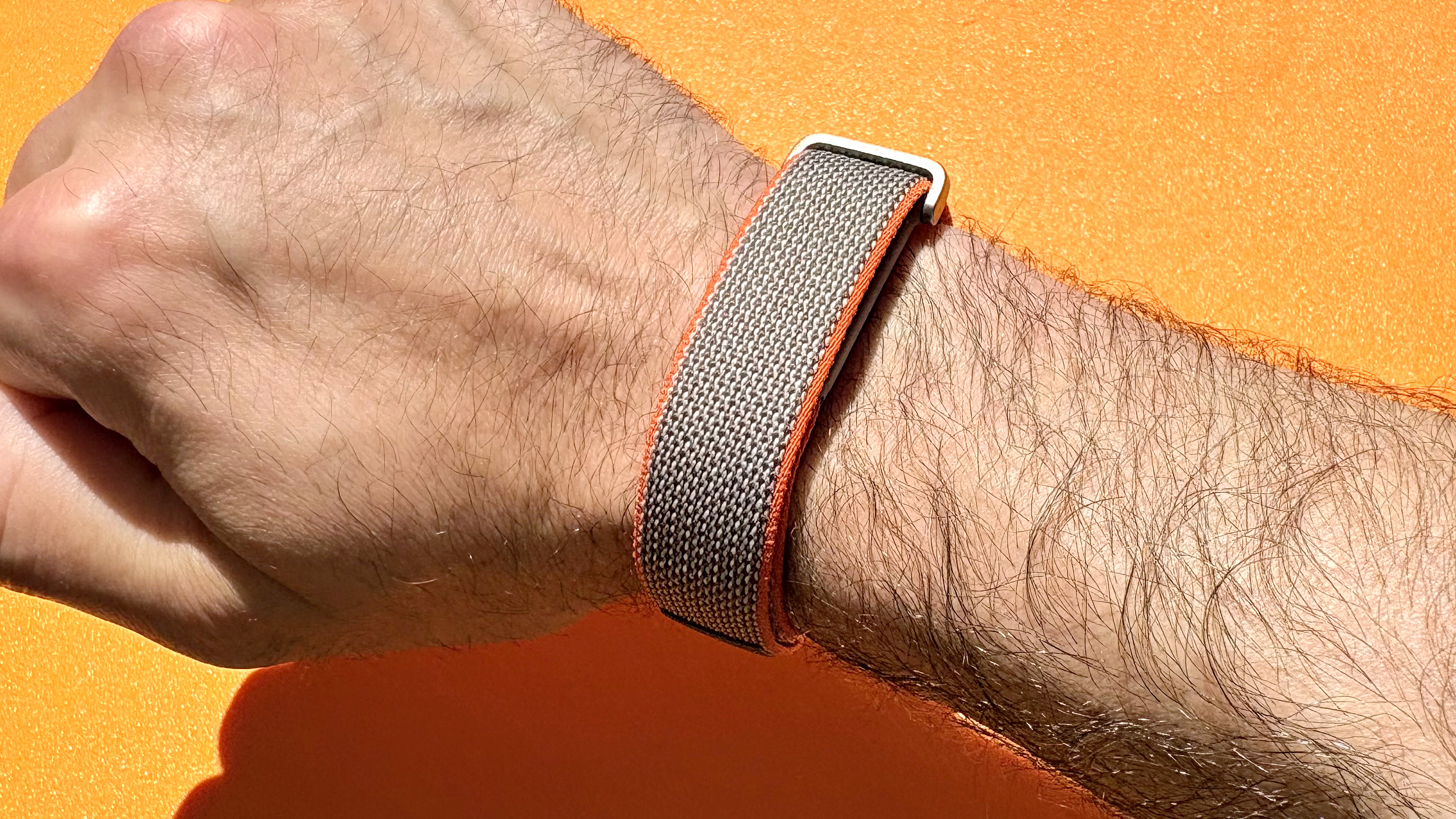Close-up of the Fitbit Air on a user's wrist with a bright orange background