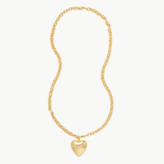 A cutout image of a long gold necklace with a big heart pendant on it