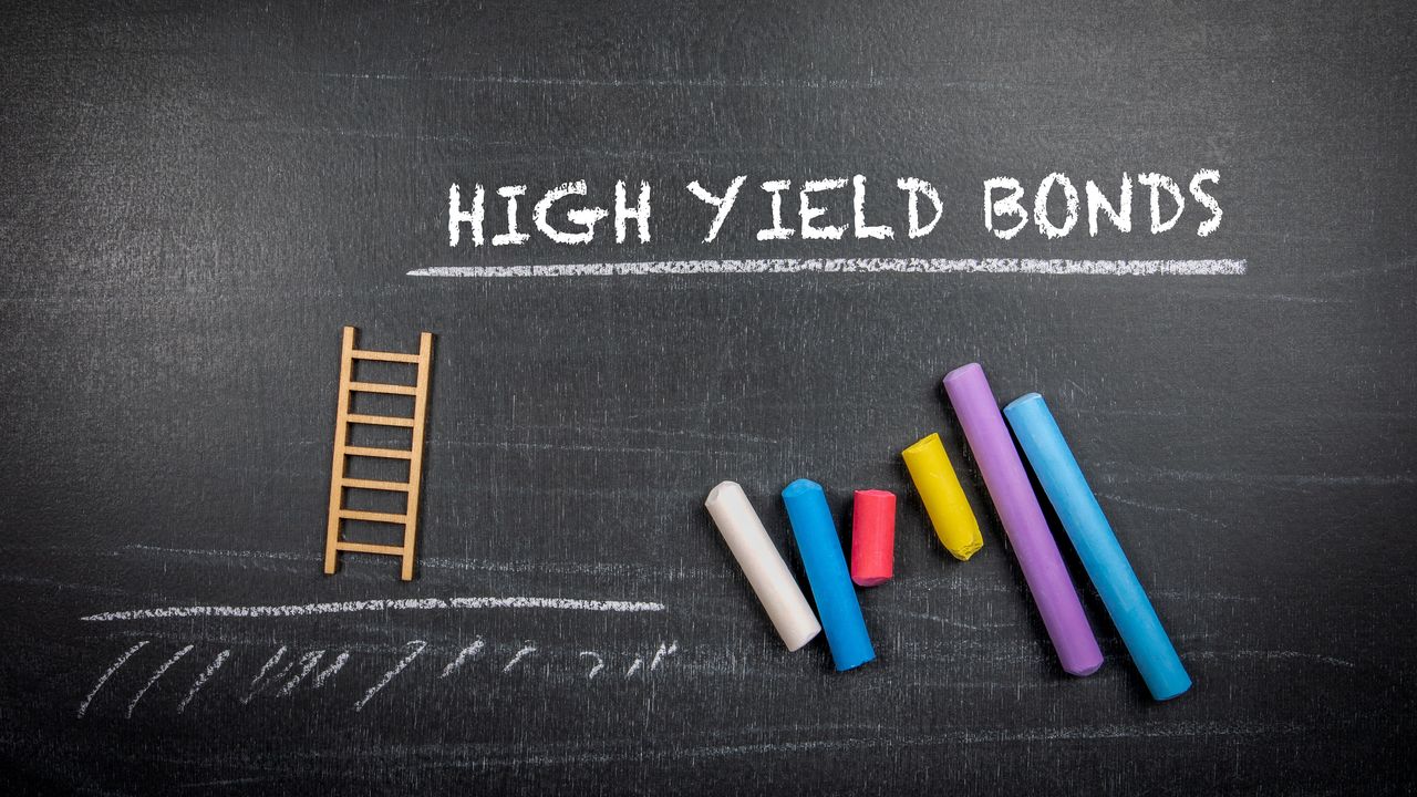 The words high yield bonds on a chalkboard above lined-up pieces of colored chalk.