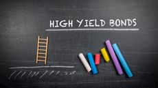 The words high yield bonds on a chalkboard above lined-up pieces of colored chalk.