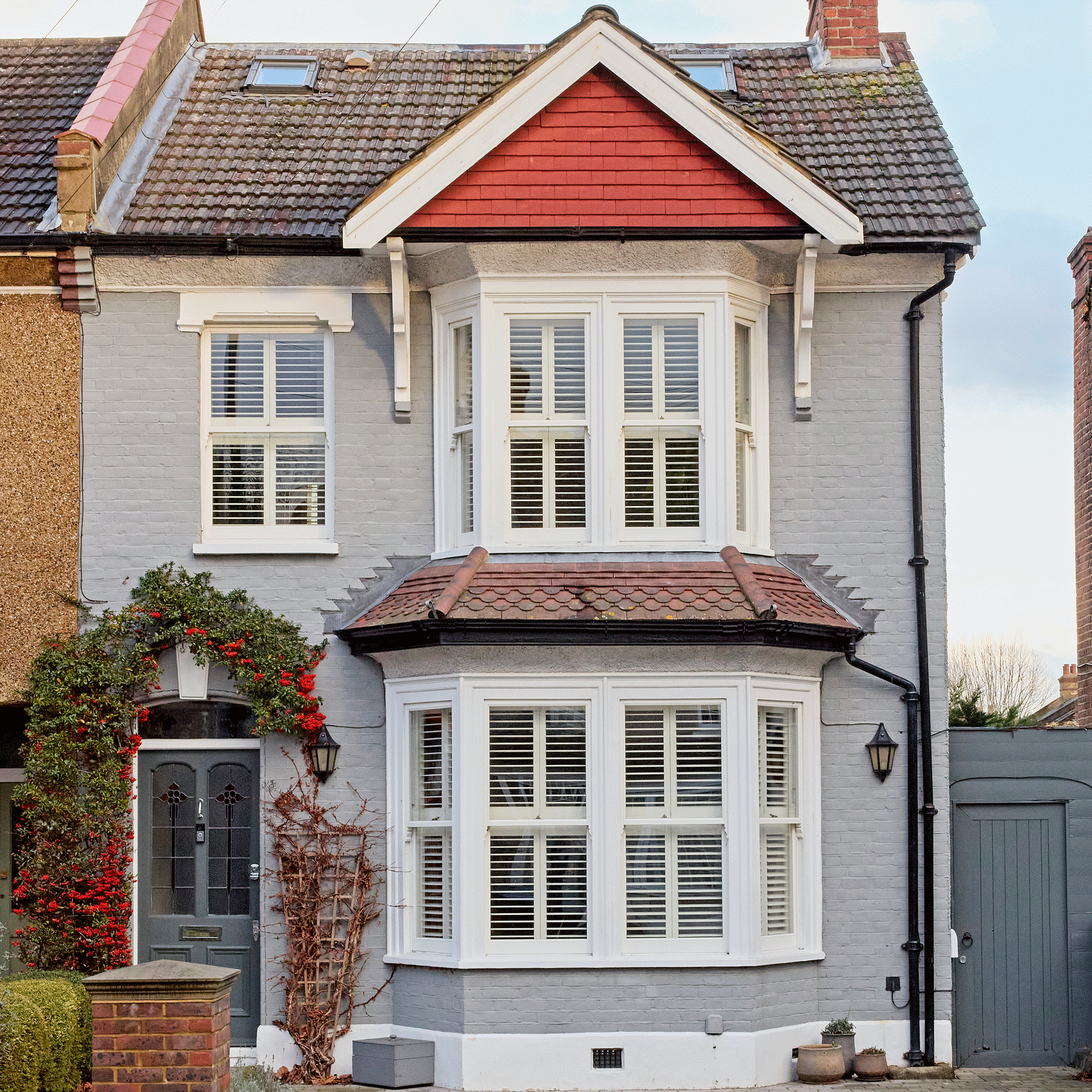 exterior of a grey painted house with a trellis beside the front door