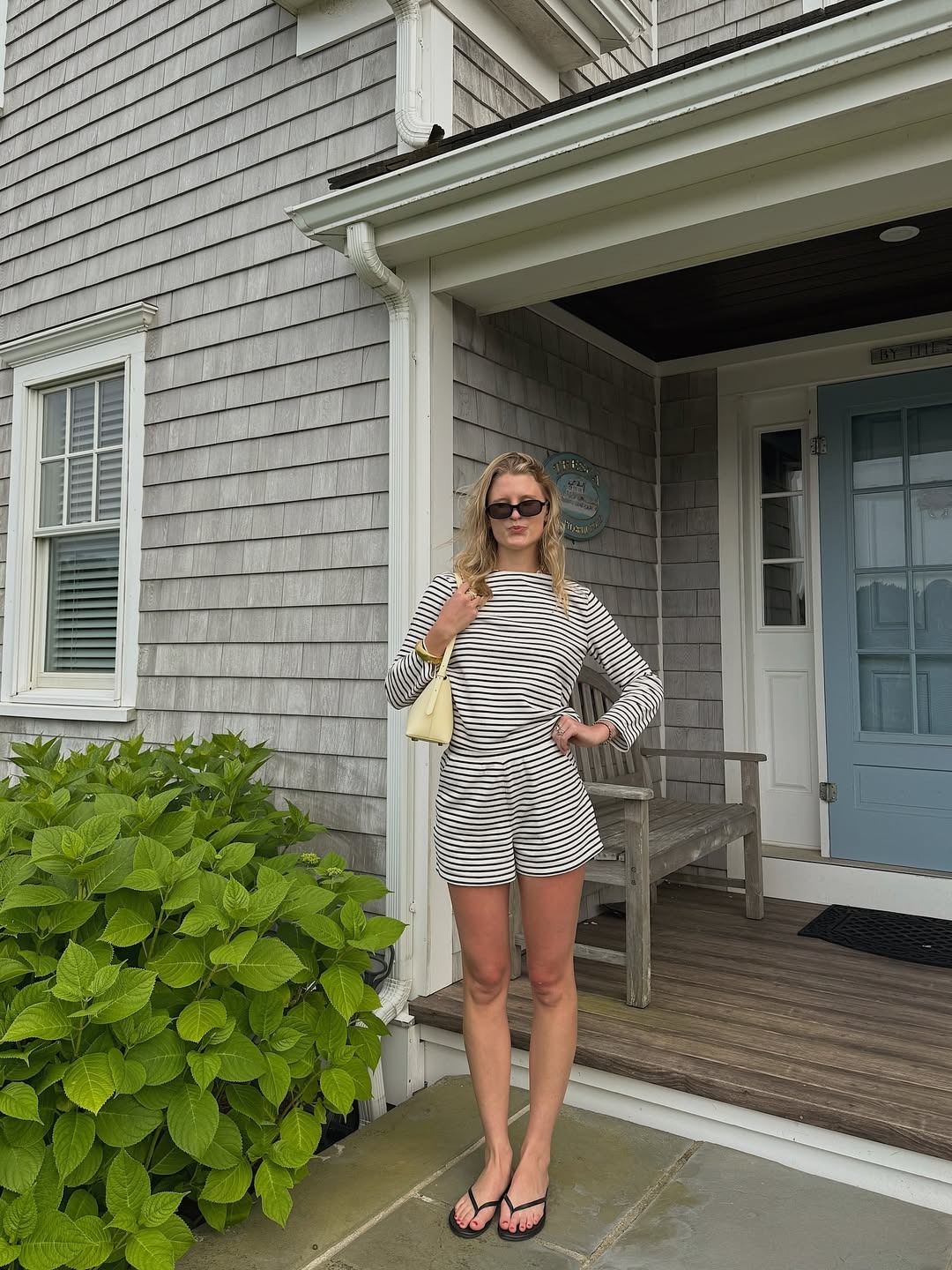 Influencer Lauren wears a striped set with a butter yellow bag and black flip flops.