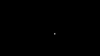 photo of the moon as a small grayish dot against the blackness of space