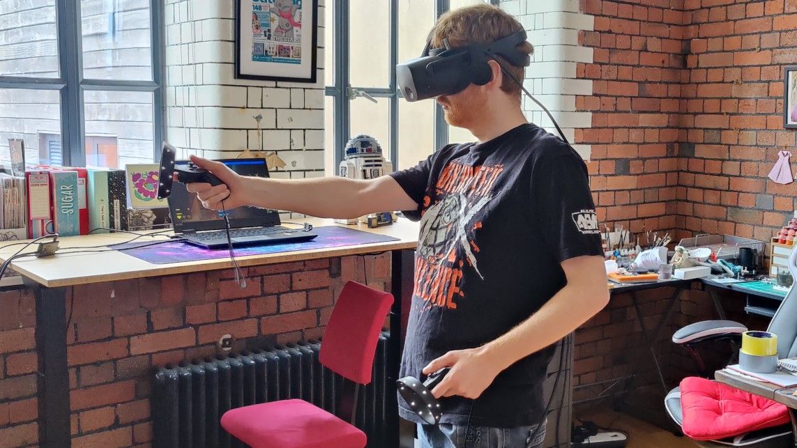 Man playing with HP Reverb G2 VR headset and controllers. He has one arm outstretched.