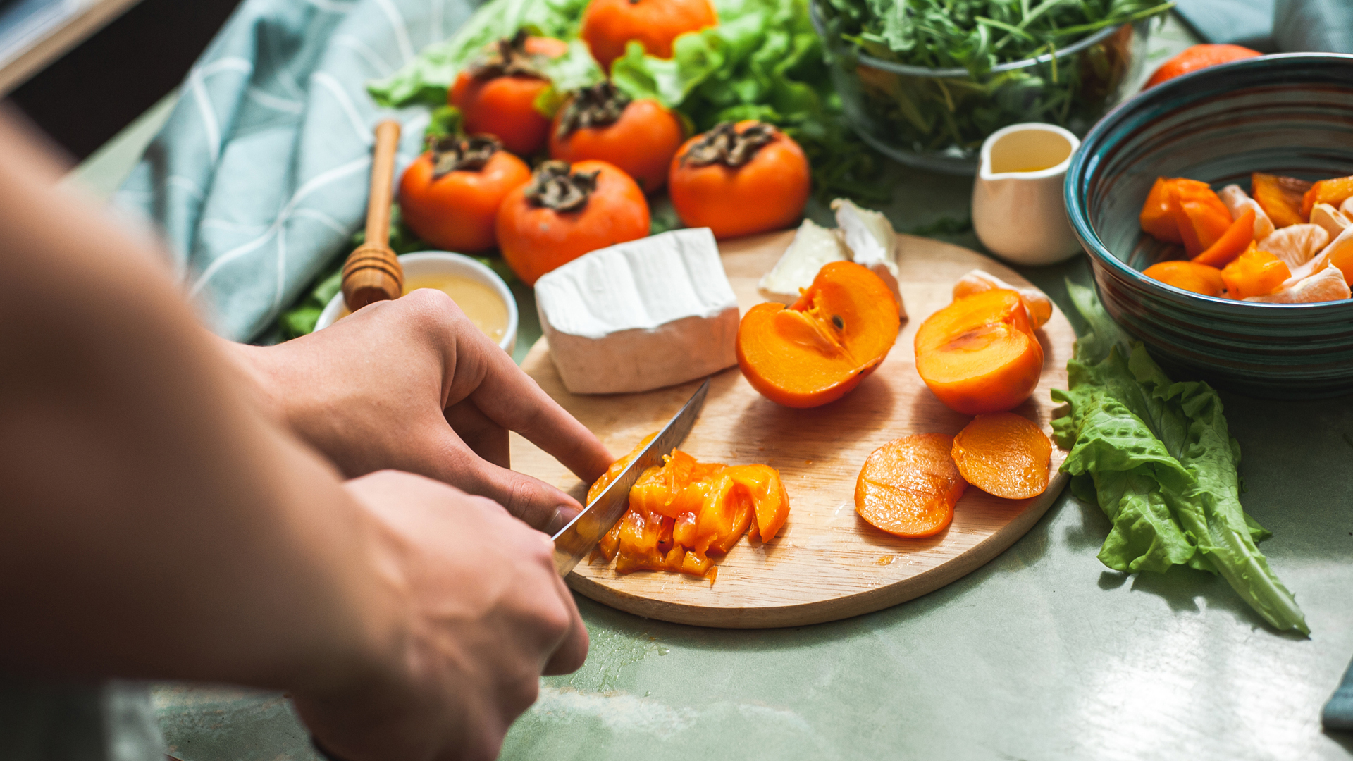 person cutting tangerine for dinner to serve with a salad