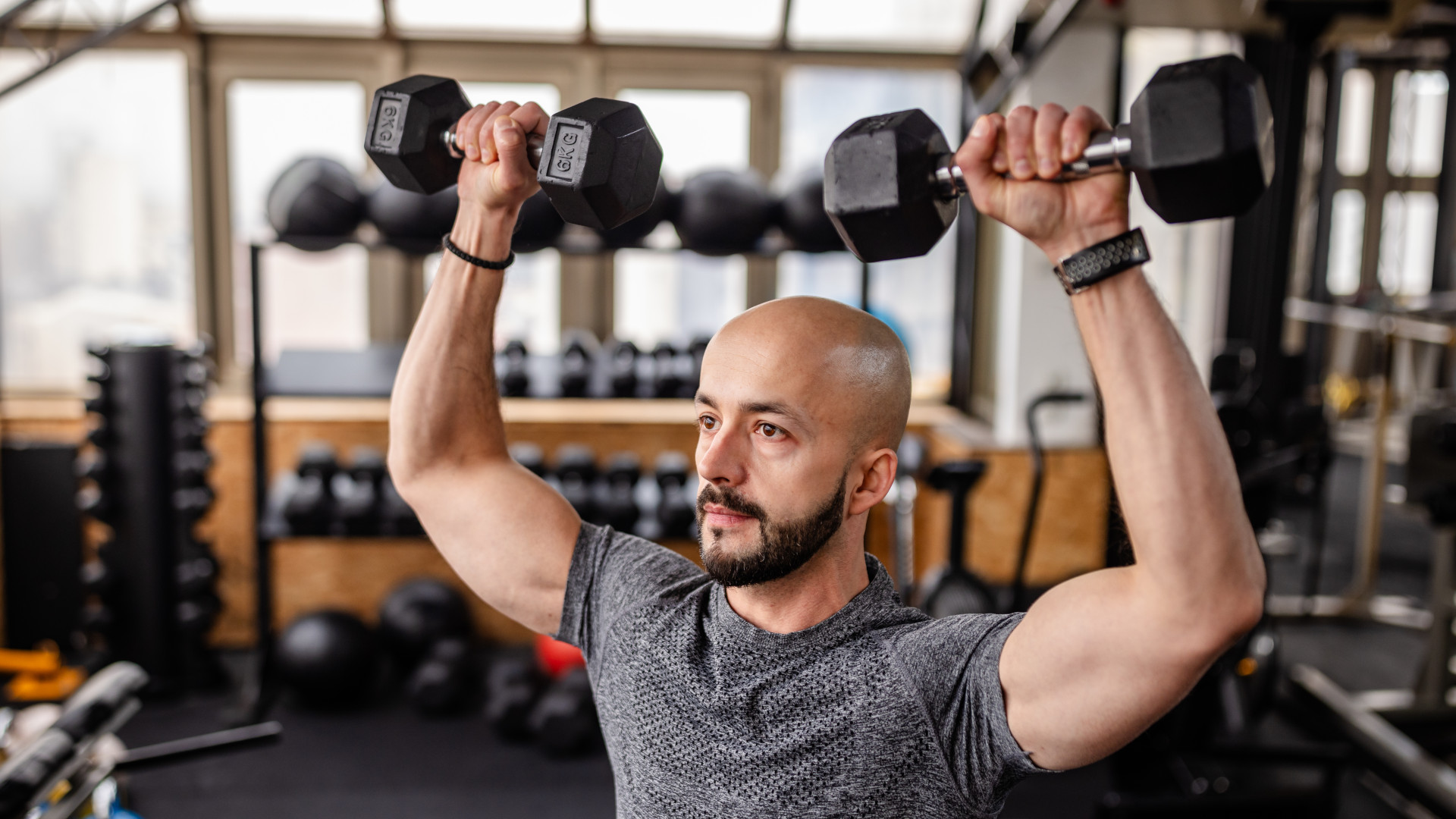 A man performing a dumbbell overhead press in as part of his full-body dumbbell workout