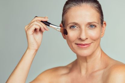 A woman applying powder foundation with a brush