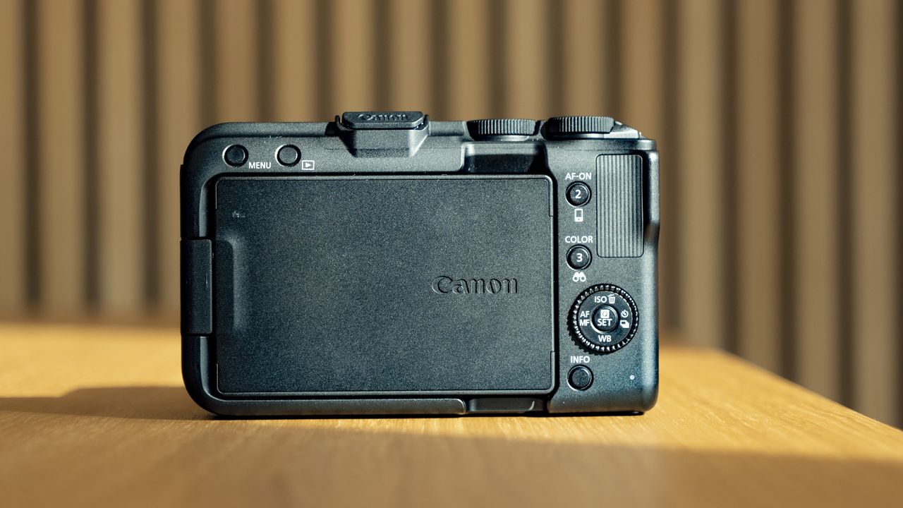 Rear of the Canon EOS R50 V, on a wooden table, screen folded away