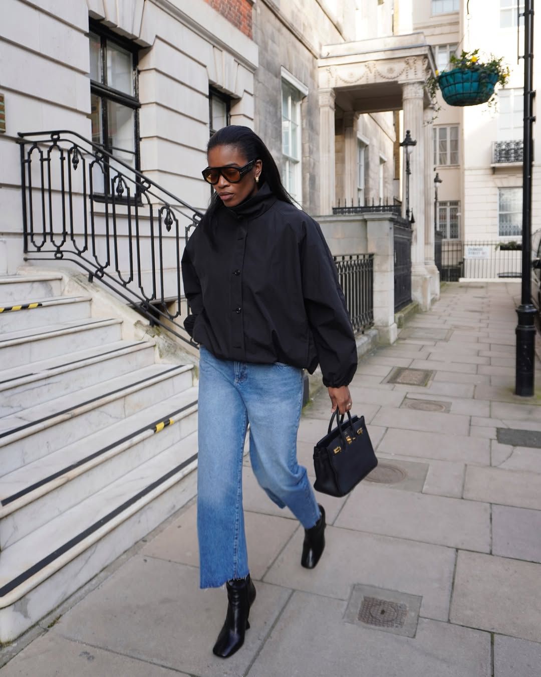 @nlmarilyn wears black bomber jacket, jeans, black boots and black bag