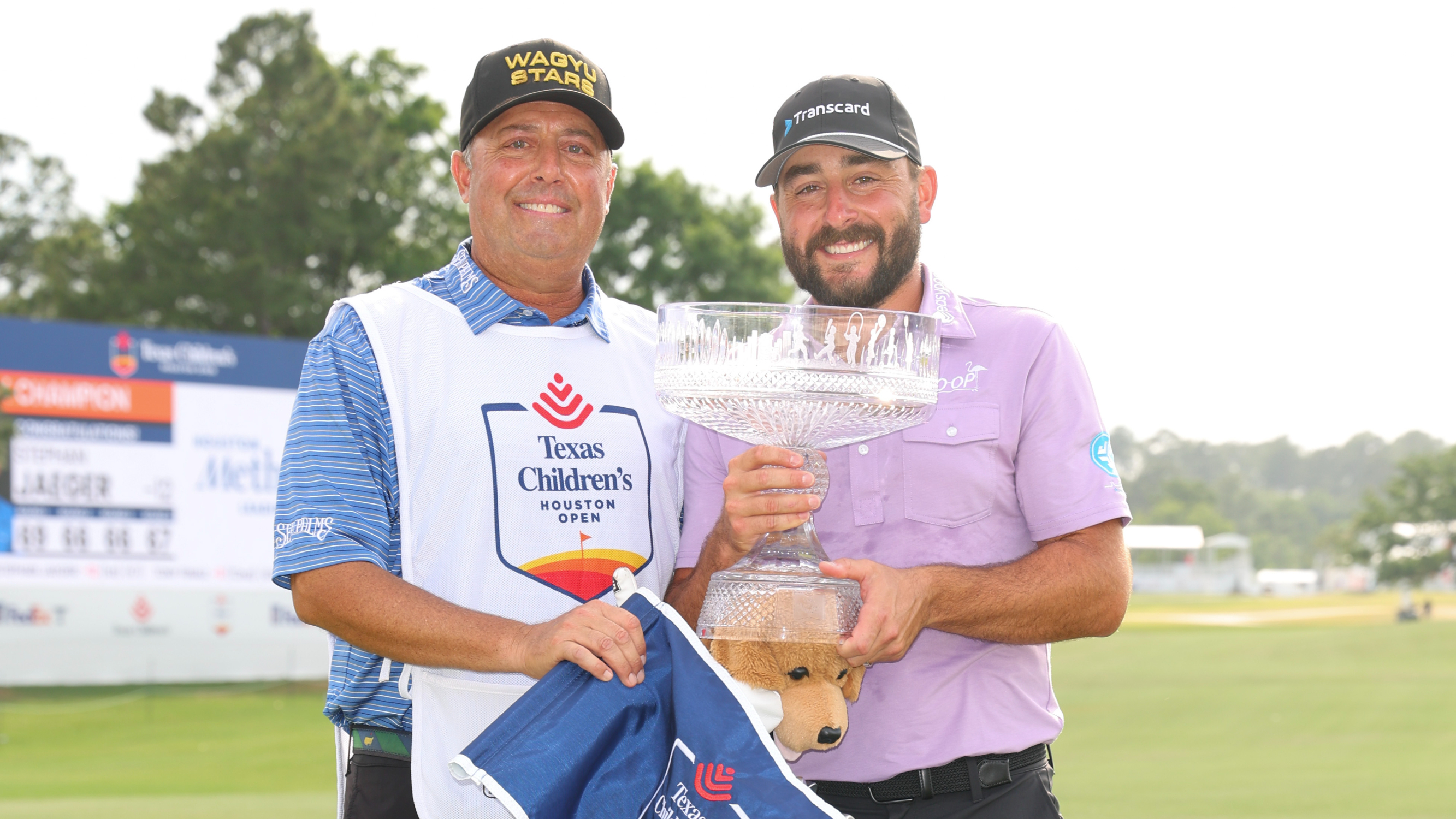 Stephen Jaeger holding the 2024 Houston Open Trophy with his caddie Henry Diana