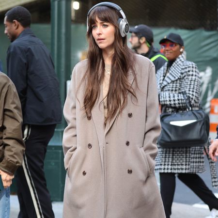 Dakota Johnson wears a tan peacoat, chestnut brown jeans, and black lug-sole boots.