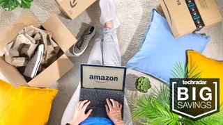 Amazon logo on a laptop sat on a number of pillows on the floor