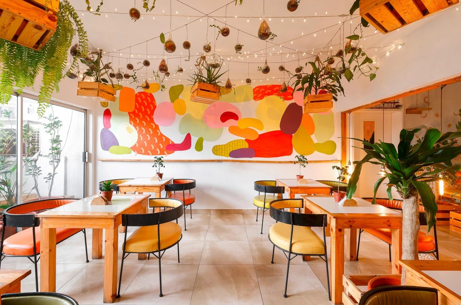 A texturally decorated hotel houses plenty of trailing plants, wooden furniture, and colorful and tactile art installations.