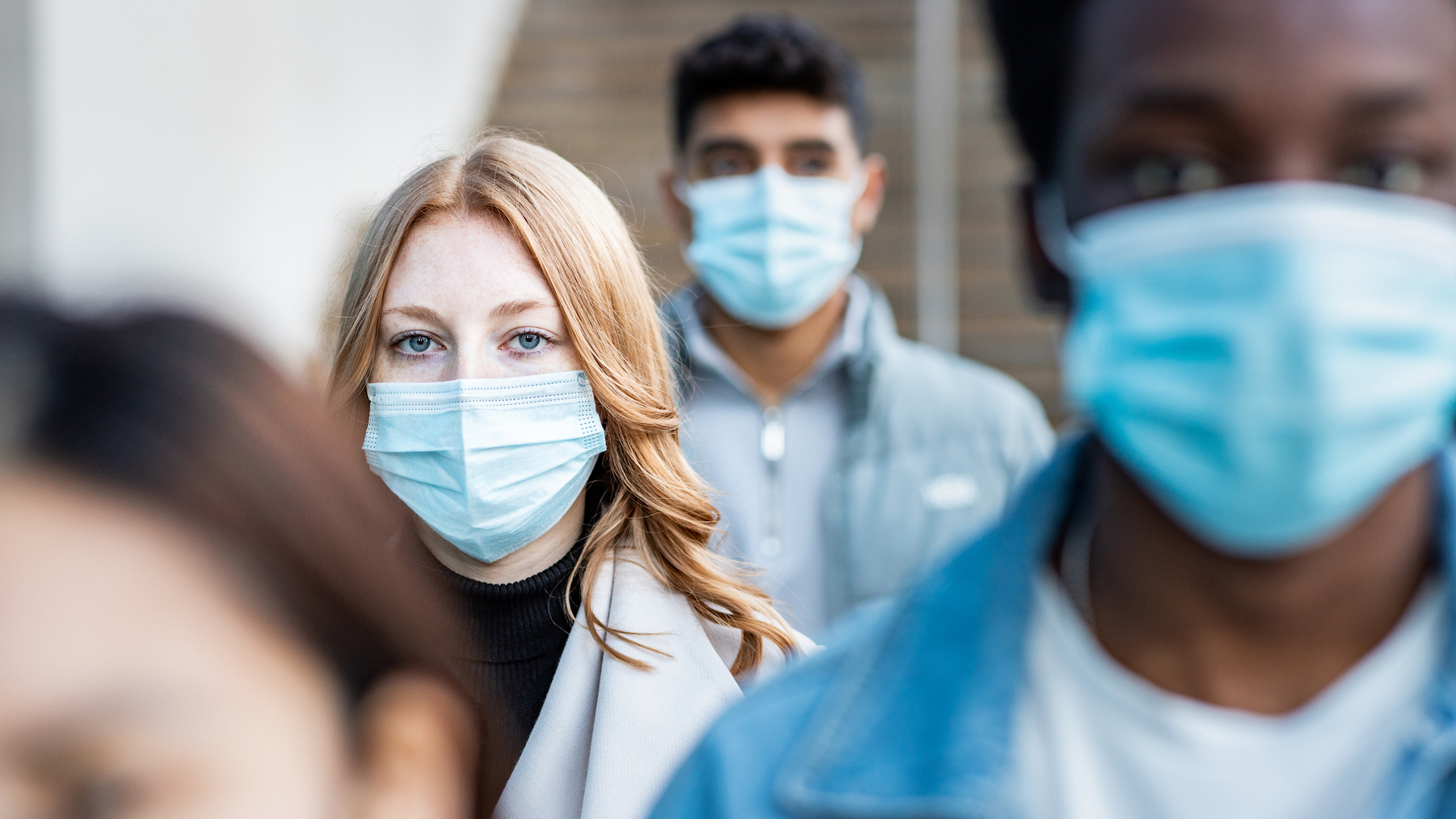 Uma fotografia de um grupo de pessoas usando máscaras cirúrgicas azuis.