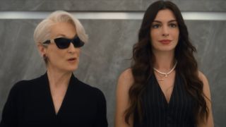 From left to right: Meryl Streep as Miranda and Anne Hathaway as Andy in The Devil Wears Prada 2. They're standing in an elevator and Mirdanda is wearing sunglasses while talking to Andy. 