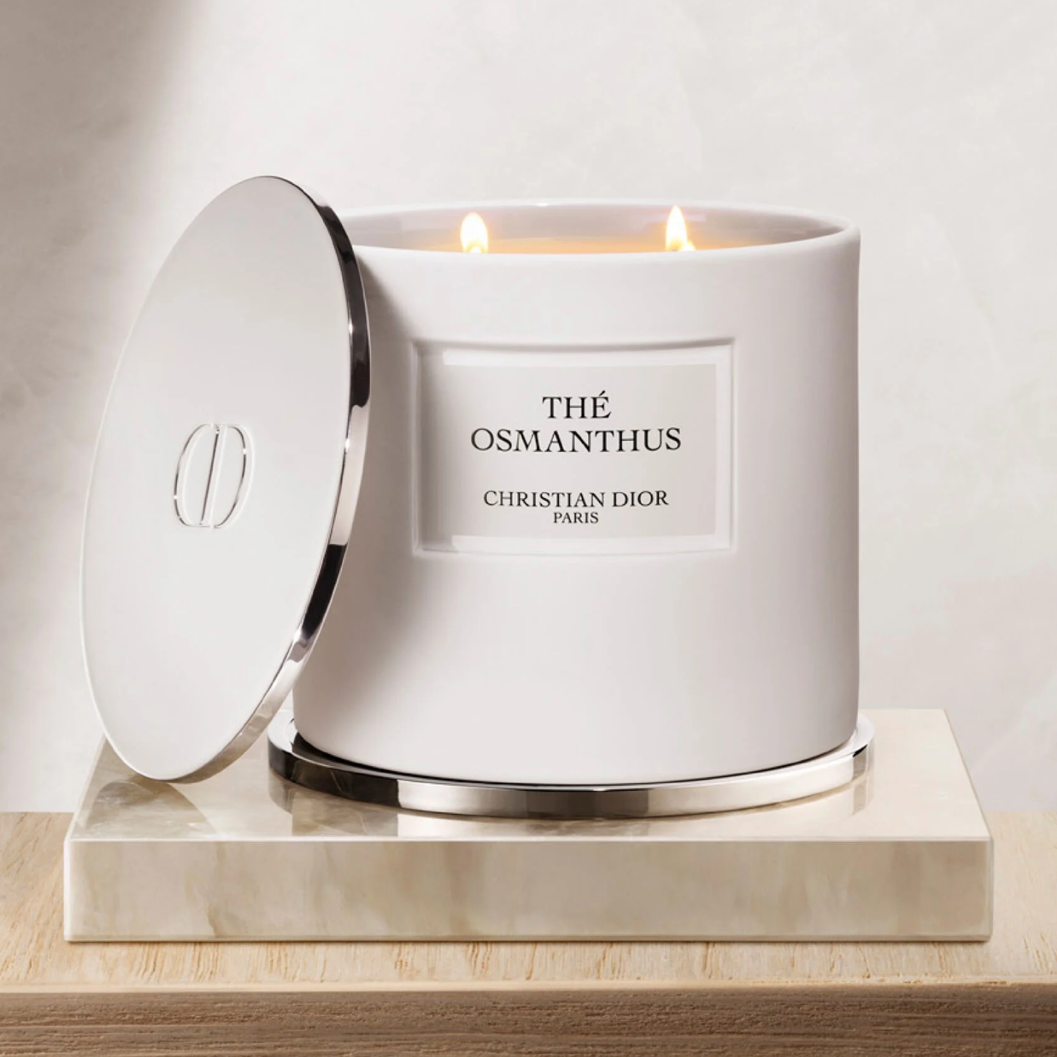 A white candle with a chrome lid on a marble tablet