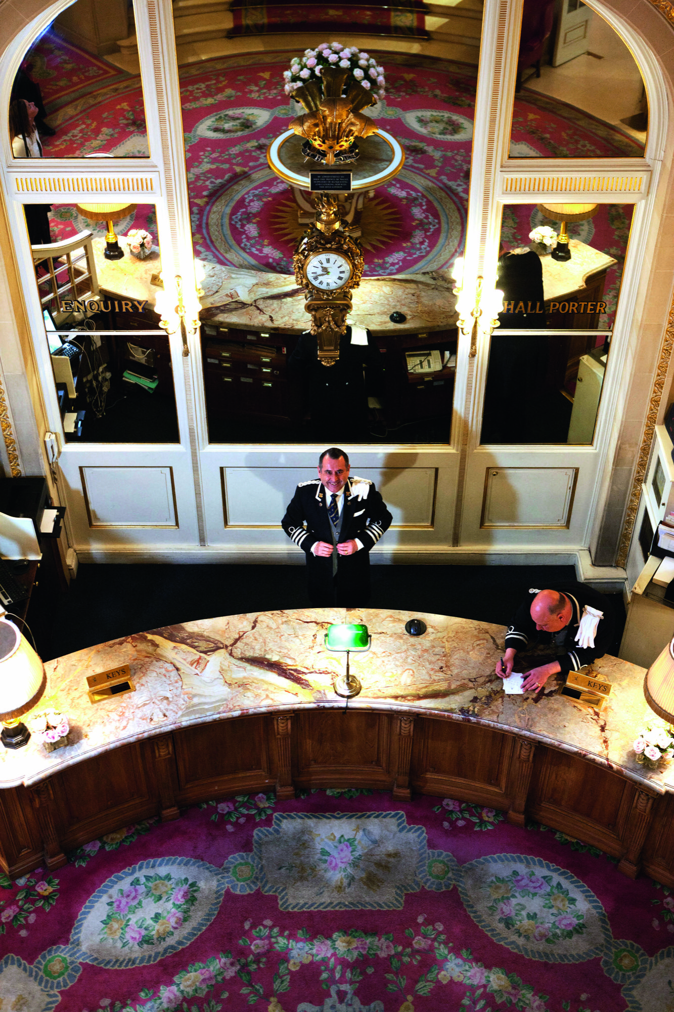 Photo of Michael deCozar, at the front desk of the Ritz, with a large mirror behind him.
