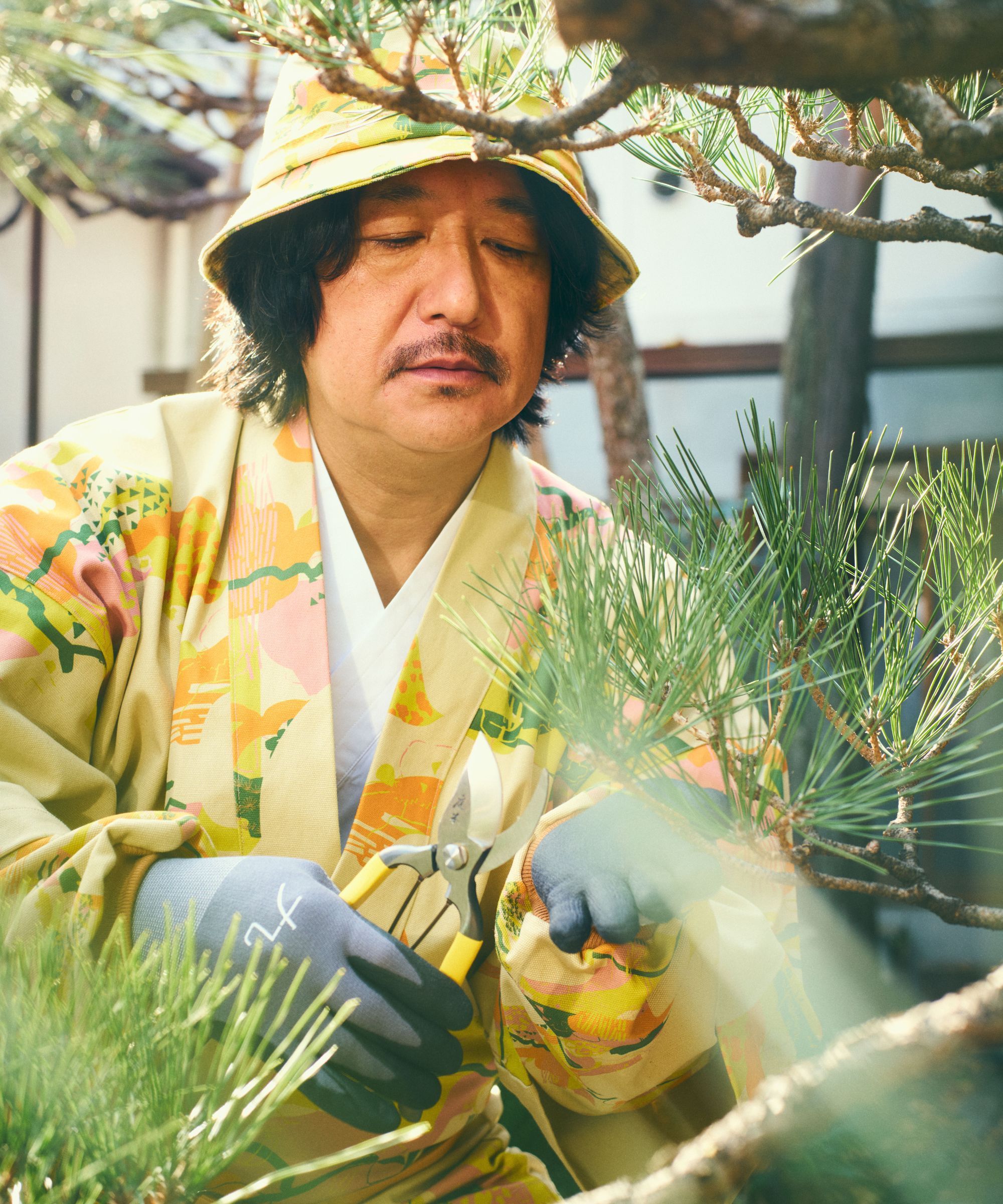 man cutting tree with Niwaki Camo Collection wearing a robe and bucket hat