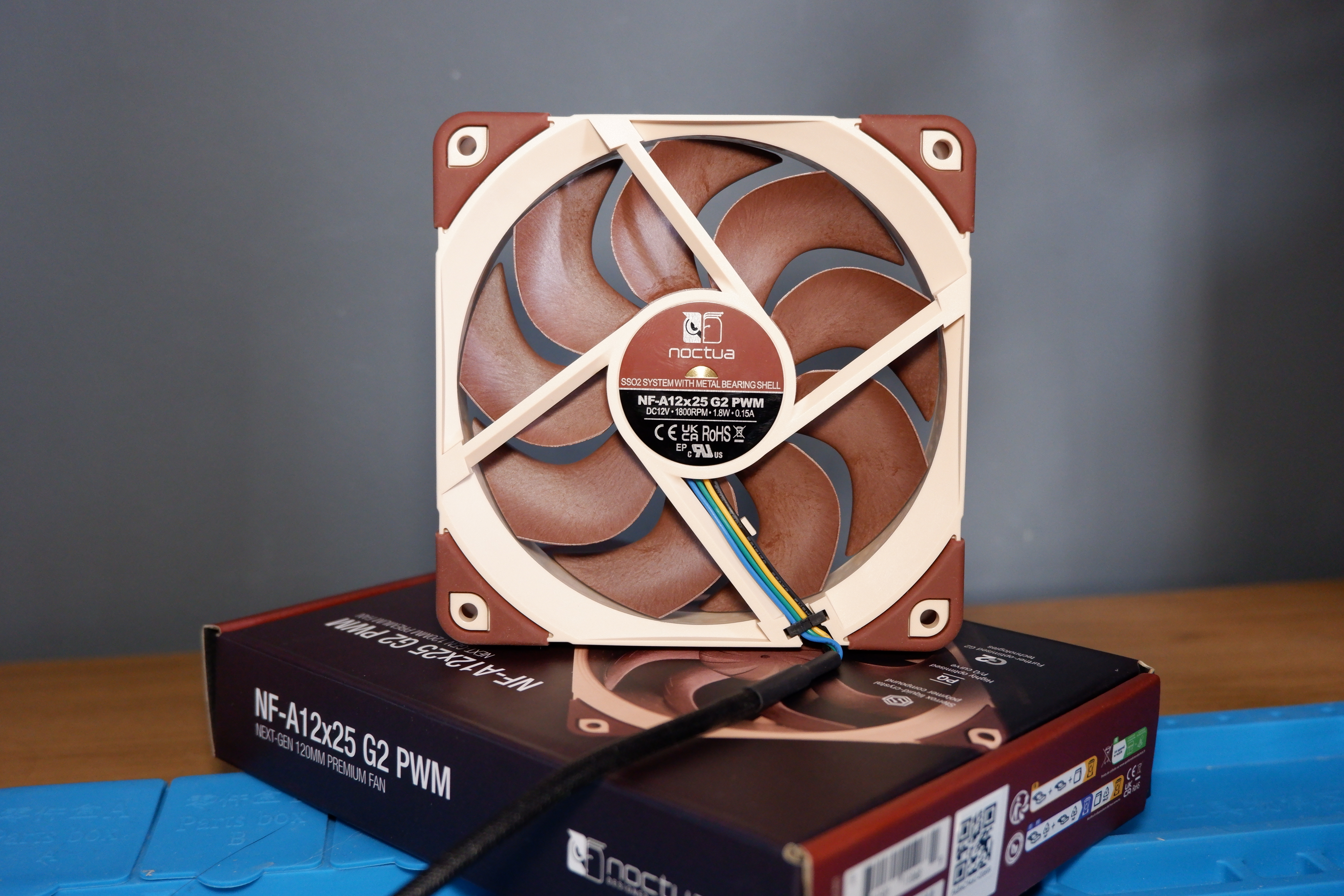 A set of Noctua NF-A12x25 G2 PC fans on a desk with packaging.
