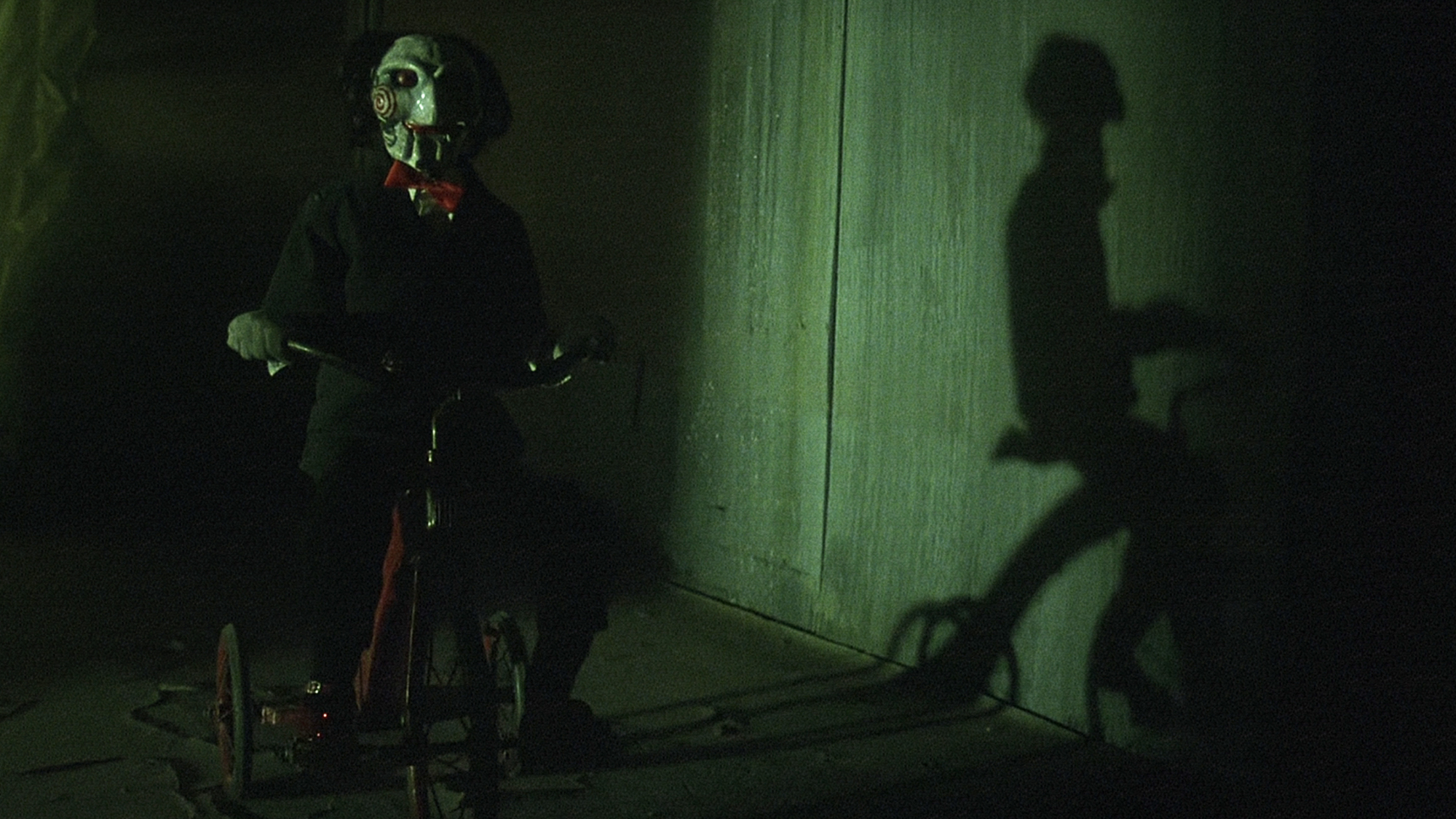 Billy the Puppet as he appears in the first Saw film, riding his bike.