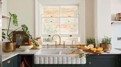 a classic kitchen showing a large Belfast double sink with fluted detailing, an aged brass kitchen tap, a separate hot water tap and separate rinse