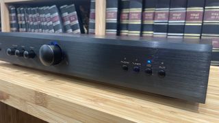 Rotel A8 integrated amplifier slight angle on wooden hi-fi rack in front of bookcase