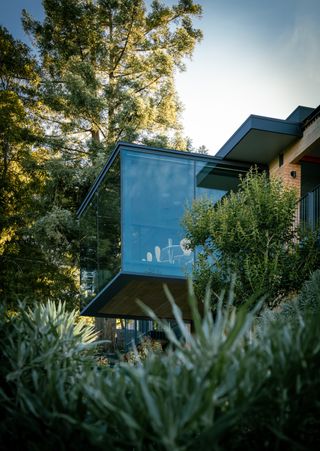 jewel box by red dot studio, a house jutting out of a leafy hill and looking out to views from large glazed side