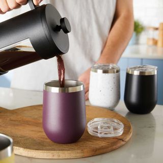 Man pouring coffee from black cafetiere into double walled insulated tumblers