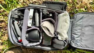 Nomatic LUMA Camera Pack open on the ground outdoors and showing the contents of the backpack