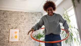 Woman using hula hoop in living room