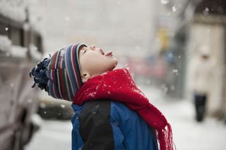 A child catching snowflakes in their mouth.