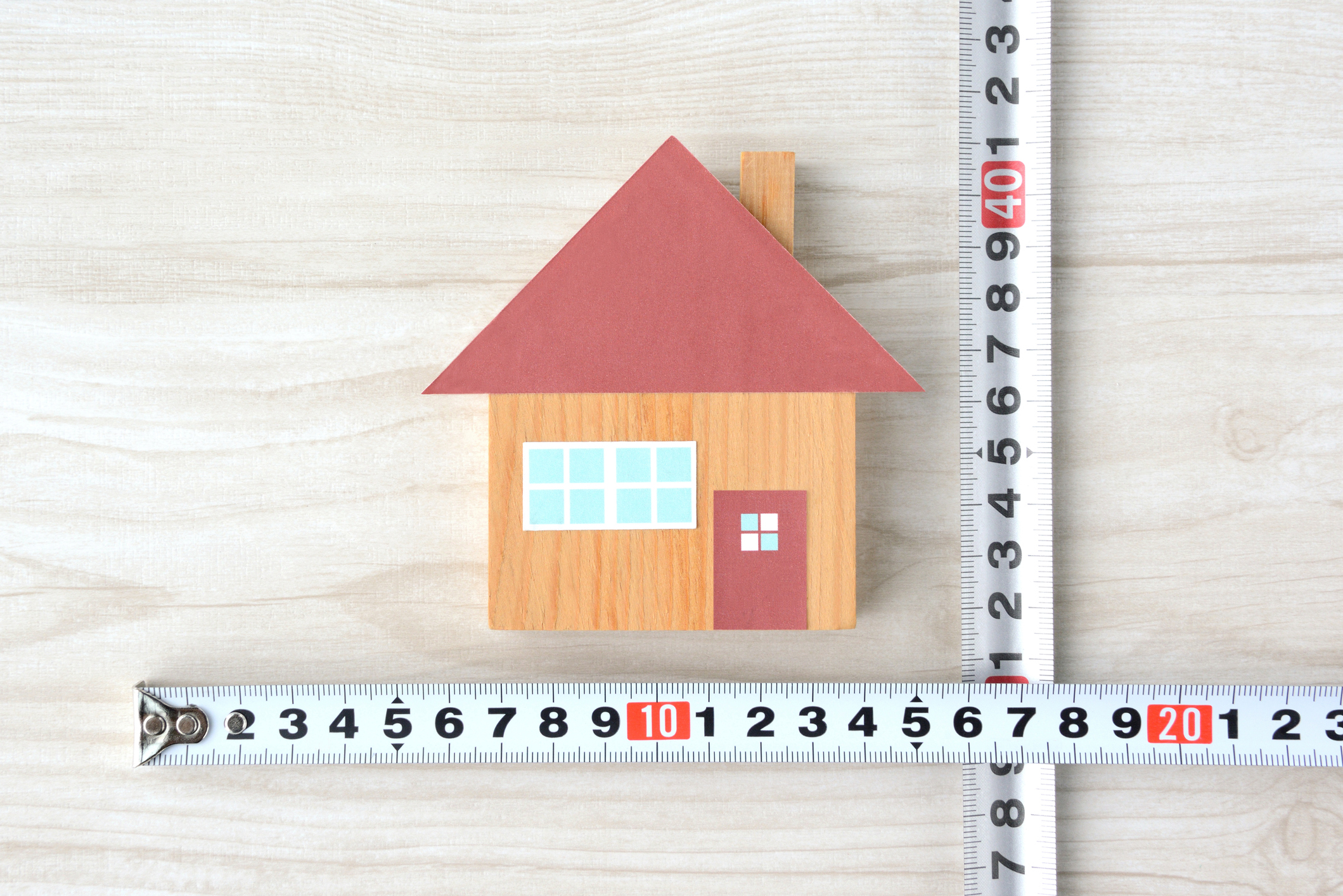 Wooden house and tape measure, measuring the house size.