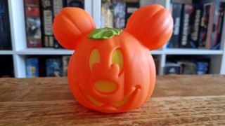 A Mickey Mouse Pumpkin decoration on a wooden table, with board games in the background