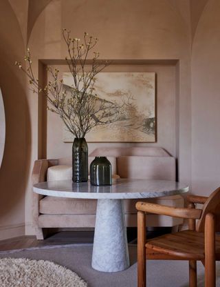 terracotta lime wash walls with round stone dining table and wooden chair