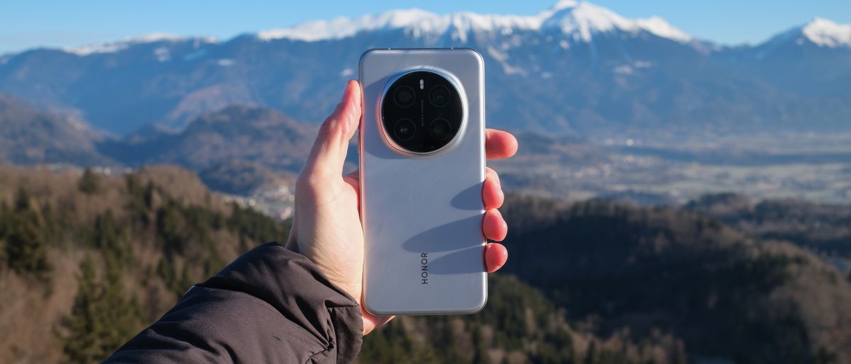 Honor Magic7 Pro phone held in a hand in front of a mountainous backdrop