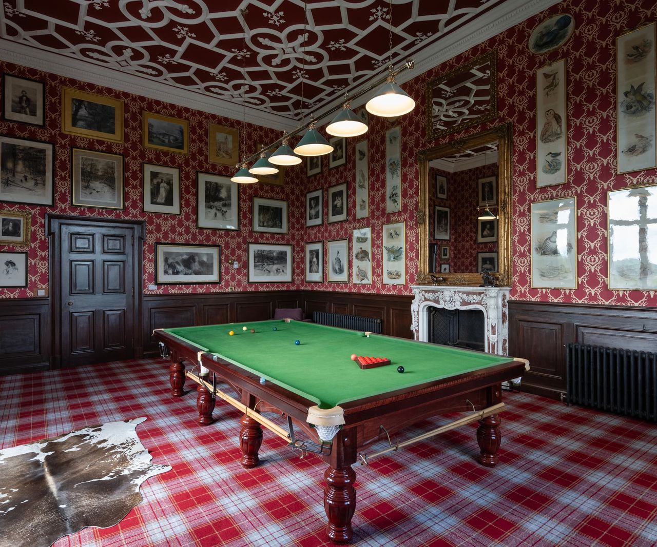 A games room with portraits on the wall and a billiards table in the middle of the room