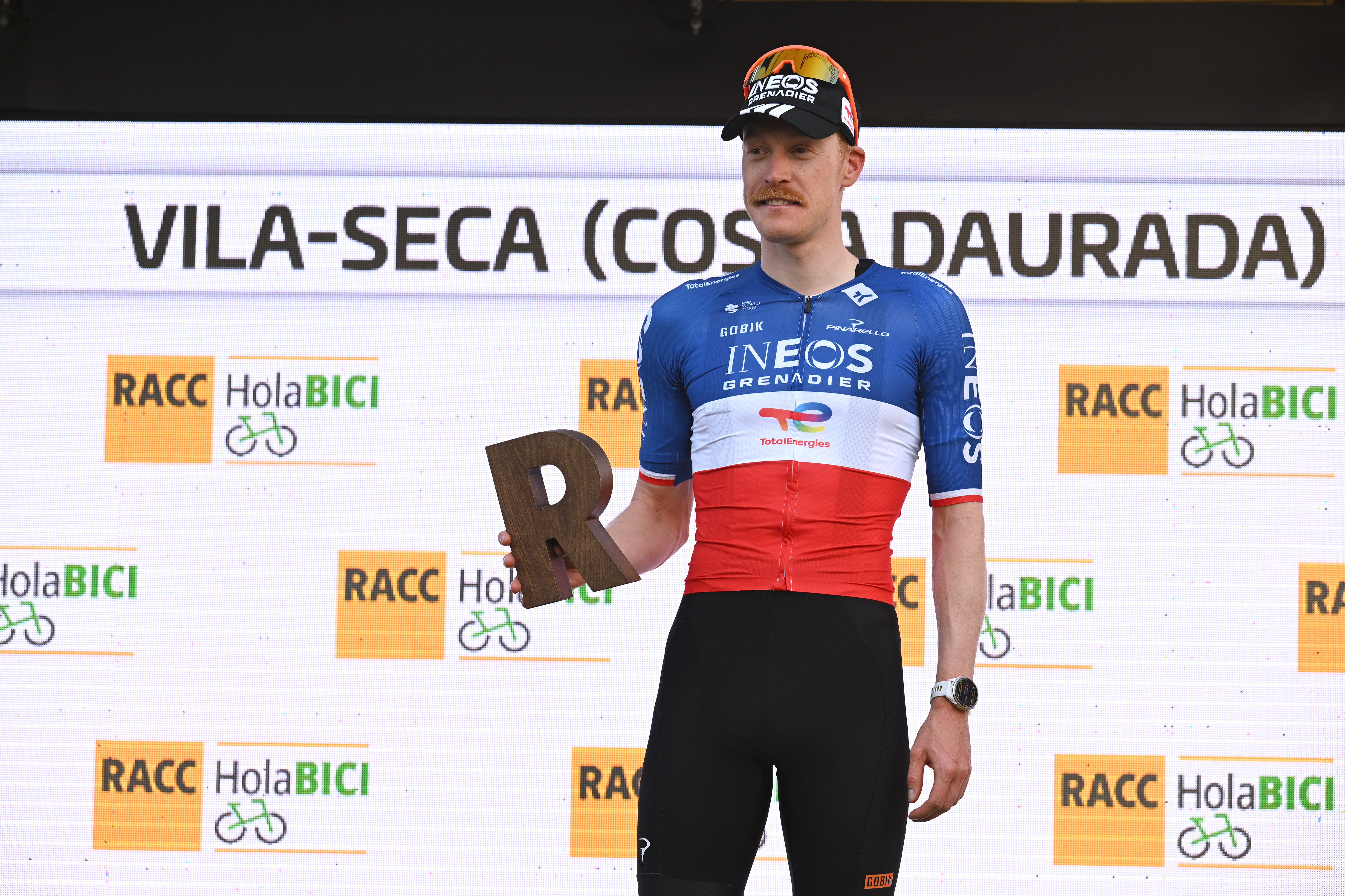 Dorian Godon celebrates victory on stage 3 with a wooden letter R at Volta a Catalunya 2026.