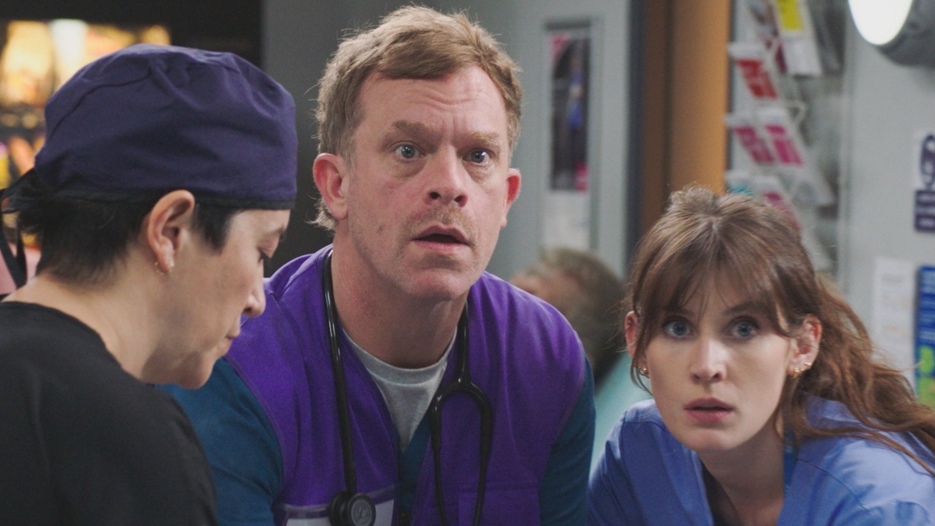 Three medics look at something along the hospital corridor