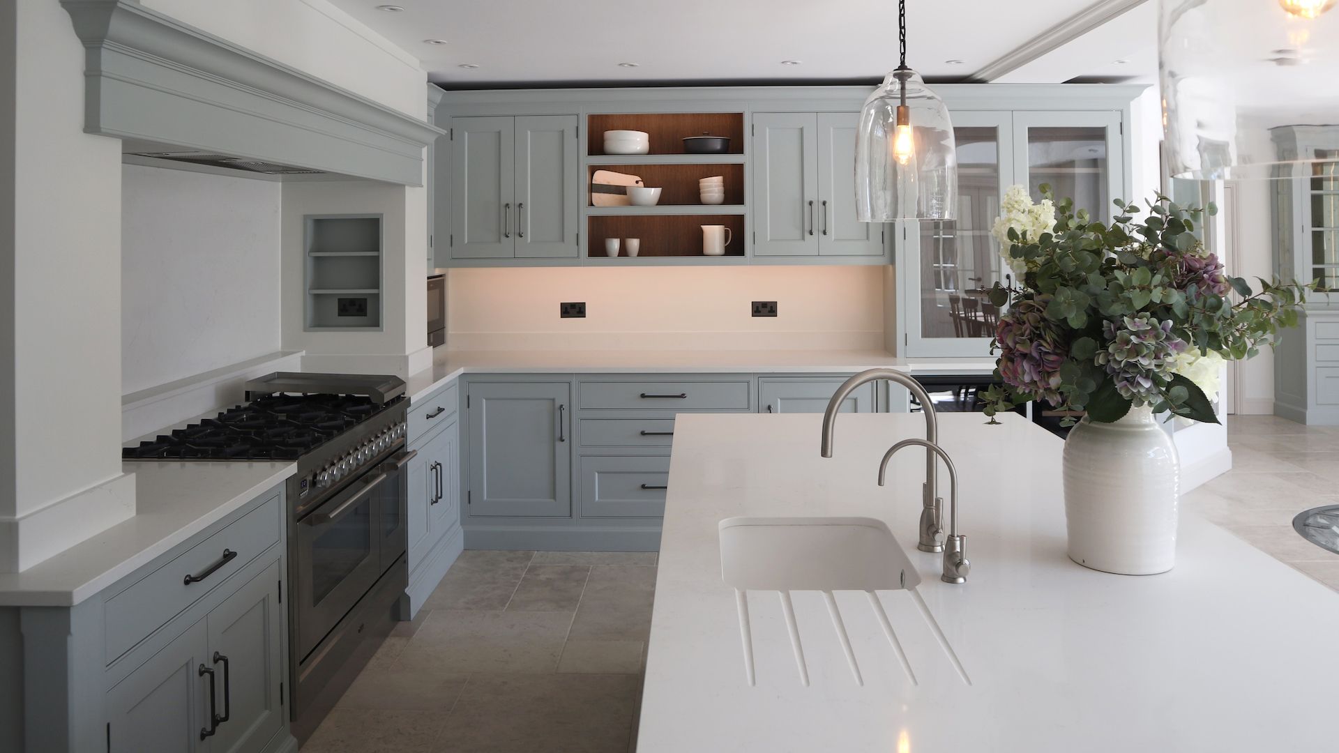 gray kictchen with white marble countertops with concealed kitchen storage in the chimney breast